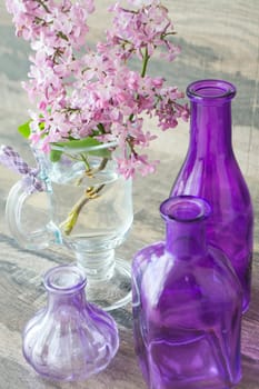Vase with beautiful small bouquet of lilac flowers with violet jars, vertical image