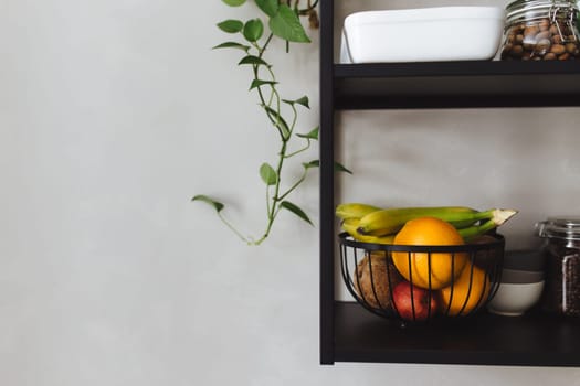 Black metal shelves in the kitchen on a gray concrete wall in a loft style. Green flowerpots. High quality photo