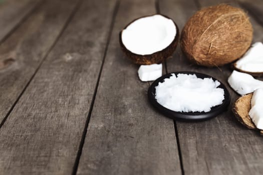 Broken coconuts on gray wooden background. White coconut fresh pulp on black plate. High quality photo