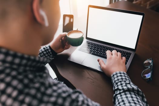Man working at laptop with cup of coffee, headphones at home. Blurred background. High quality photo