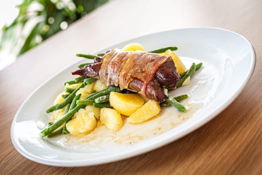 Cooked food on a white plate - pork tenderloin with bra, pine nuts and spring onions.