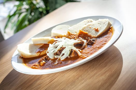 Cooked food on a white plate - beef stew with bread dumplings.