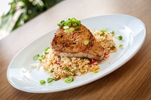 Cooked food on a white plate - tuna served on vegetable risotto.