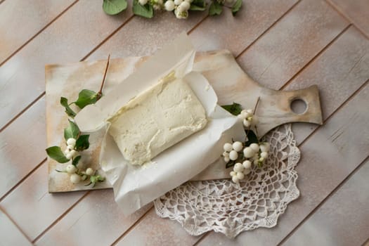 Fresh white cottage cheese on a shabby cooting board on a wooden table top view