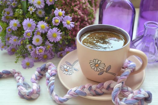 Cup of coffee in coffe mug on the wooden rustic table with violet flowers, vintage style image