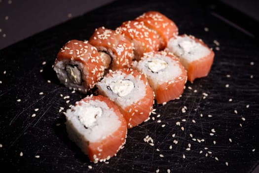 Sushi rolls set served on black board on dark background