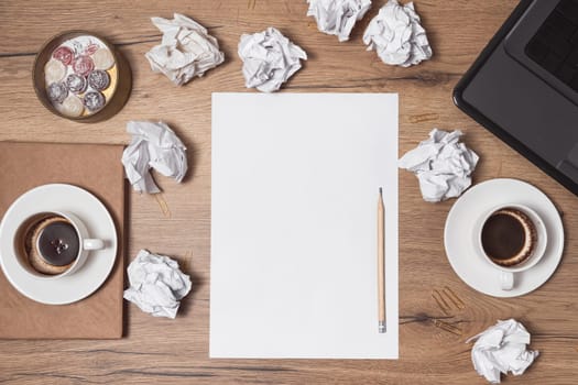 Crumpled papers scattered, empty cups of coffee on table of a creative worker. Creative crisis. Concept of stress, mental health trouble and lack of ideas.