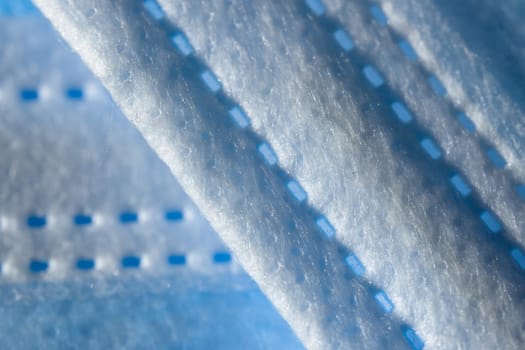 Super macro abstract close up of a 3-ply disposable face mask. Individual fibers visible along the printed paper like seam. Background with copy space