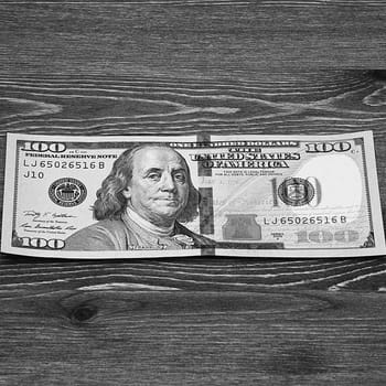 a hundred-dollar bill in cash on a dark wood table. Mockup, layout.