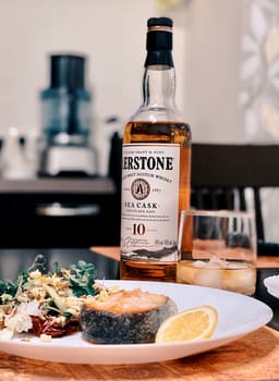 Salmon steak with a salad of herbs, spices and vegetables is served with whiskey. Supper. 07.02.2021. Samara, Russia.