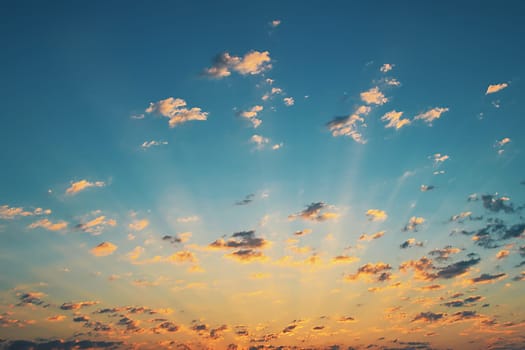 Beautiful sunrise with sun rays and clouds in the blue sky. Nature, environment.