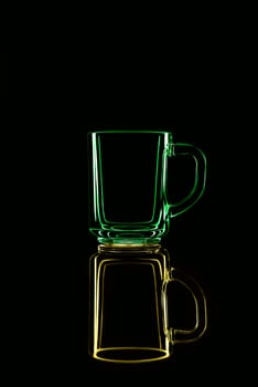 Just a glass on a black background with a reflection. Yellow and green. Isolated.