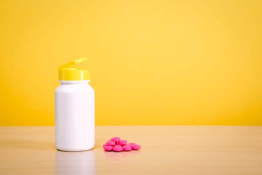 A white jar with scattered red pills on a yellow background. Place for the label, logo, layout.
