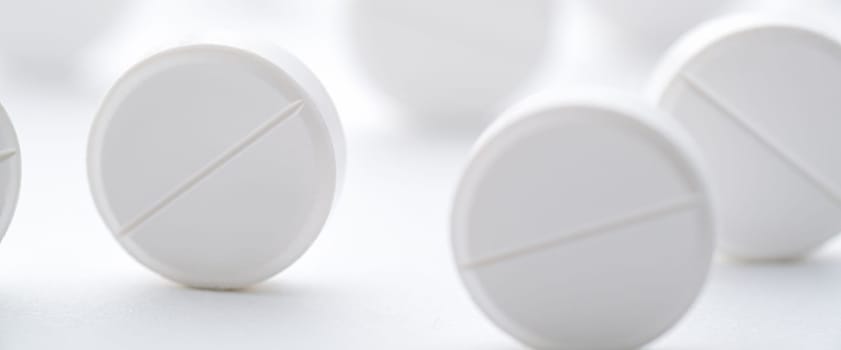 A pile of white pills scattered on a bright white background. Selective focus. Mockup layout, template.