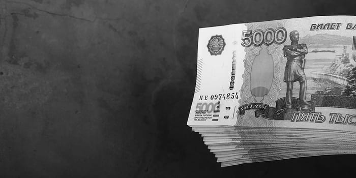 Russian cash banknotes of five thousand rubles, the bundle hangs on a gray background, there is a place for the inscription and text. Layout, mockup.