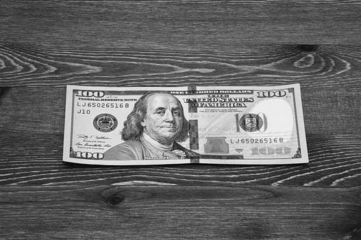 a hundred-dollar bill in cash on a dark wood table. Mockup, layout.