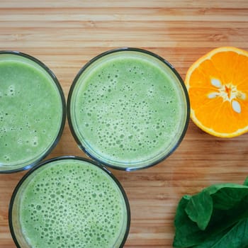 Arrangement of a fresh green healthy smoothies and fruits on a wooden background.