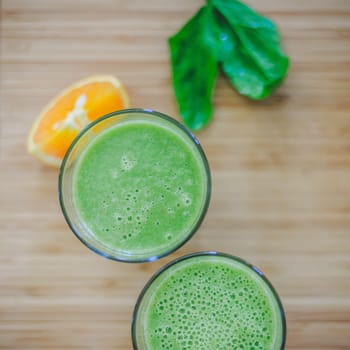 Arrangement of a fresh green healthy smoothies and fruits on a wooden background.