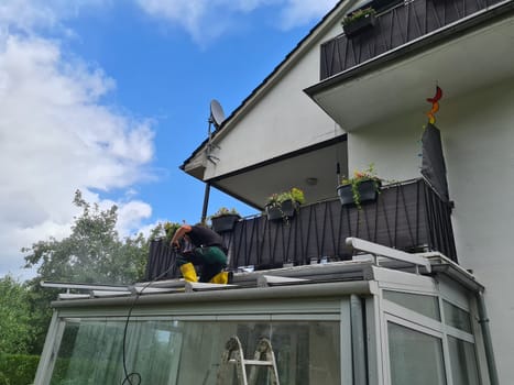 Man power washing conservatory roof and windows