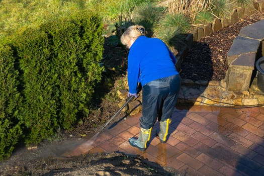 Worker cleaning driveway with gasoline high pressure washer splashing the dirt,professional cleaning services.High pressure cleaning,lower body.