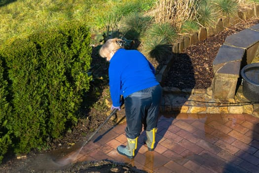 Patio Pressure Cleaning. Caucasian Woman Washing His Concrete Floor Patio Using High Pressured Water Cleaner.