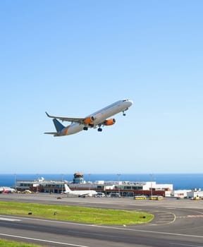 Airplane taking off International Airport skyward view, planes parked by terminal, sunshine, seascape, Funchal, Madeira