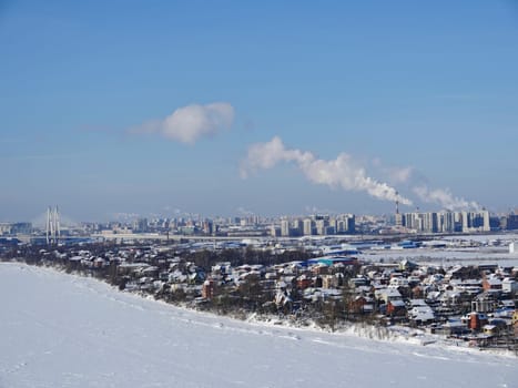 Bird's eye view of a suburban village on the banks of a river in winter, a river and small houses under the snow, a cozy calm suburban life in nature