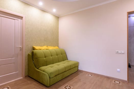Fragment of the living room interior in a small apartment, the sofa stands against the wall