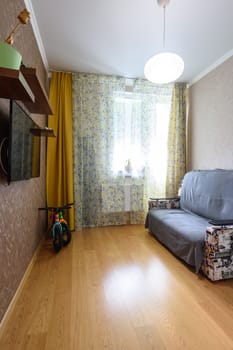Anapa, Russia - March 1, 2021: Interior of a small modest room with a sofa and a TV on the wall