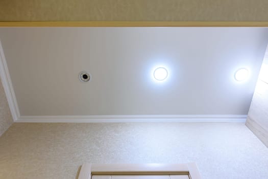 Stretch white matte ceiling in the hallway, one of the lamps burned out and twisted