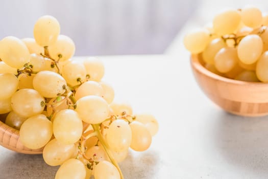 A branch of organic white grapes in wooden bowl