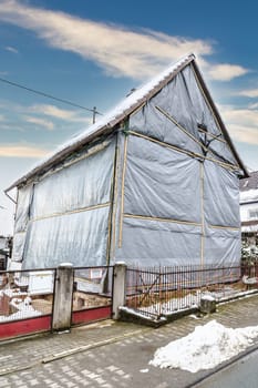 House covered with tarpaulin in winter