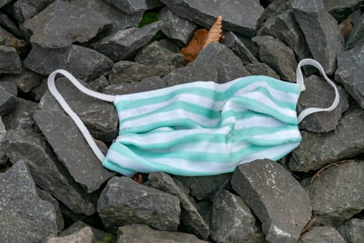 Used fabric face mask lies on the stone floor