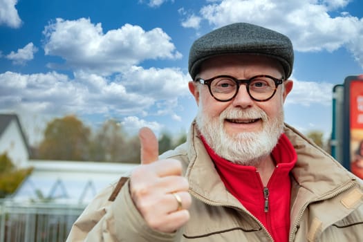 Outdoor Portrait from a optimistic Senior in winter cloth shows thumb up