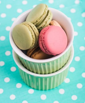 Sweet Macarons with green bowls and green fabric background