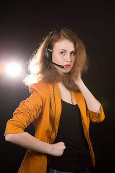 Young beautiful woman-operator with headphone smiles, it is isolated on black background.