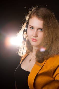 Young beautiful woman-operator with headphone smiles, it is isolated on black background.