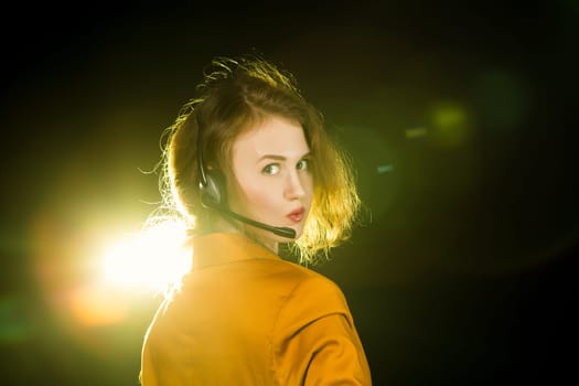 Young beautiful woman-operator with headphone smiles, it is isolated on black background.
