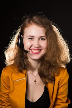 Young beautiful woman-operator with headphone smiles, it is isolated on black background.