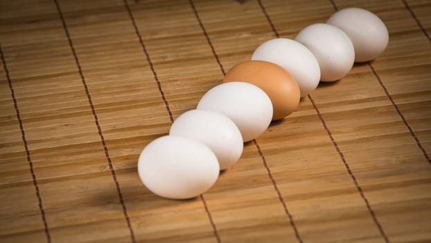 Brown and white eggs with reflection on wood background