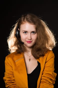 Young beautiful woman-operator with headphone smiles, it is isolated on black background.