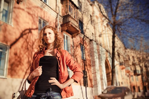 teenage girl dressed in orange jacket on the street