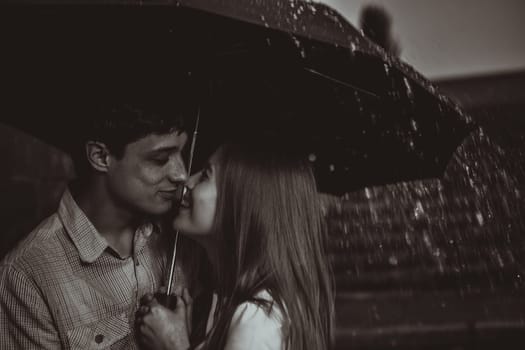 Love in the rain / Silhouette of kissing couple under umbrella
