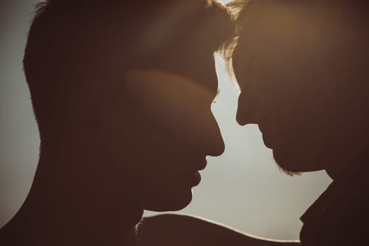 Silhouette of two men about to kiss
