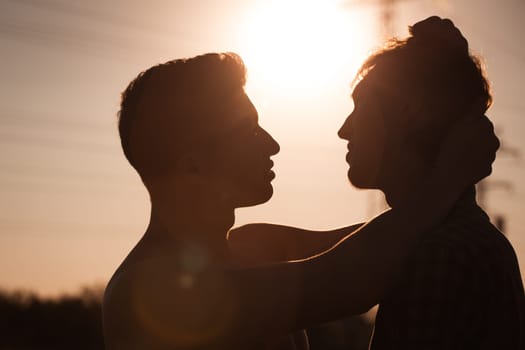 Silhouette of two men about to kiss
