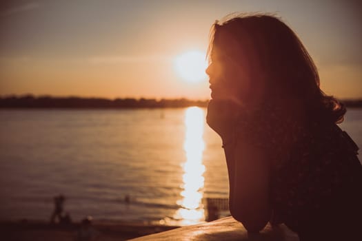 Beautiful young brunette girl sitting outdoors near the river