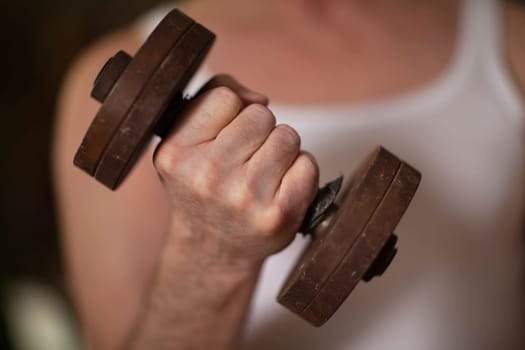 fist with iron dumbbell, man does physical exercises with dumbbells close-up, shallow depth of field