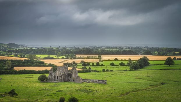 Old ruins of Hore Abbey surrounded by fields and forest, dark dramatic storm sky. Located next to Rock of Cashel castle, County Tipperary, Ireland