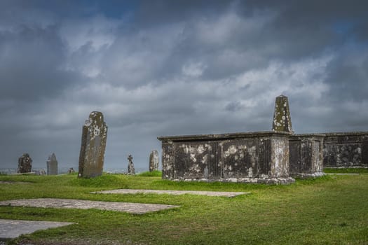 Ancient Celtic cross, gravestone and tombs with dramatic storm sky in background in Rock of Cashel, Ireland