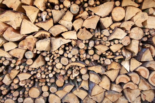 Natural wooden background - detailed chopped firewood. Wood stacked and ready for winter pile of wooden logs.